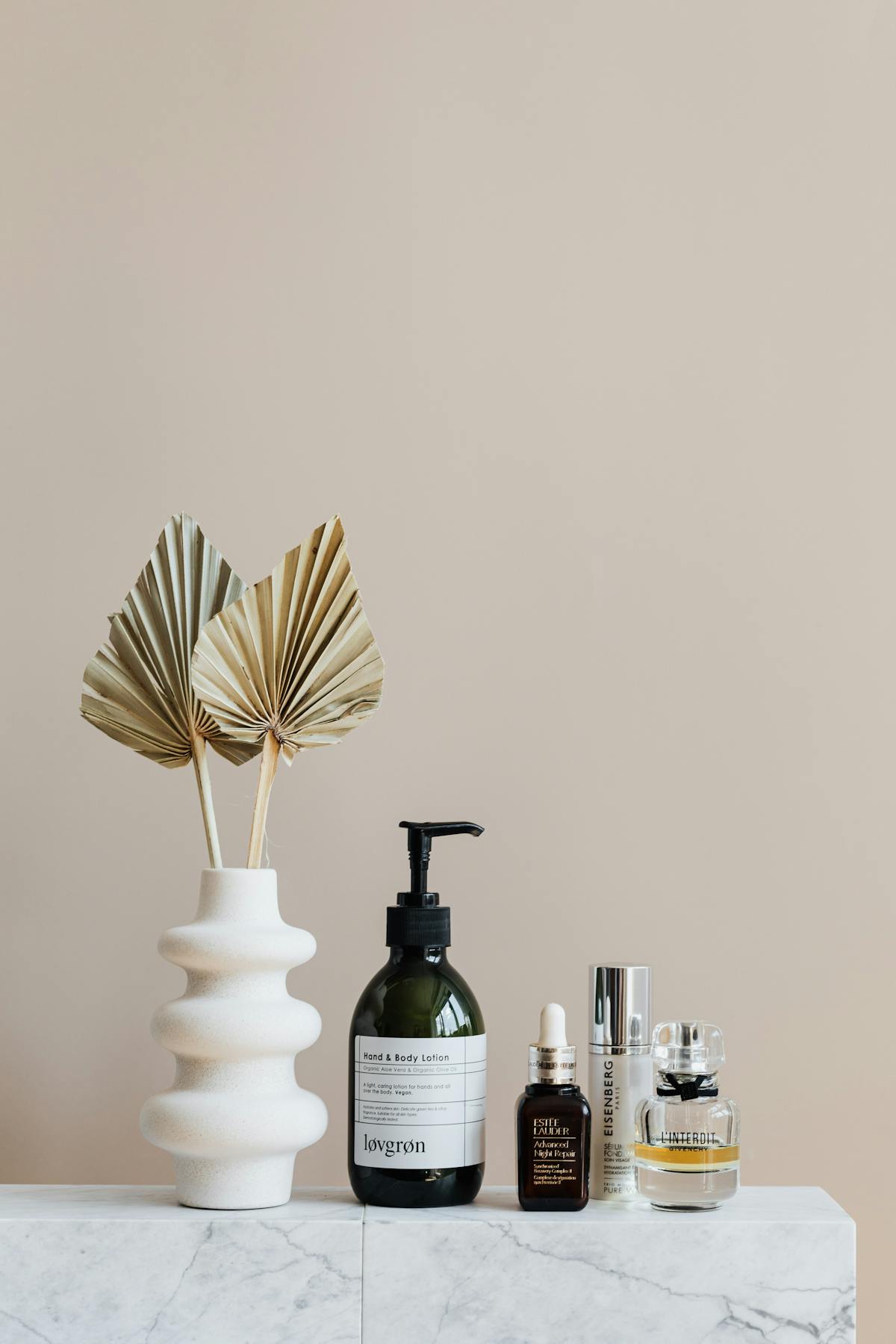 Amber dropper bottle of essential oil with skincare ingredients arranged on a marble surface