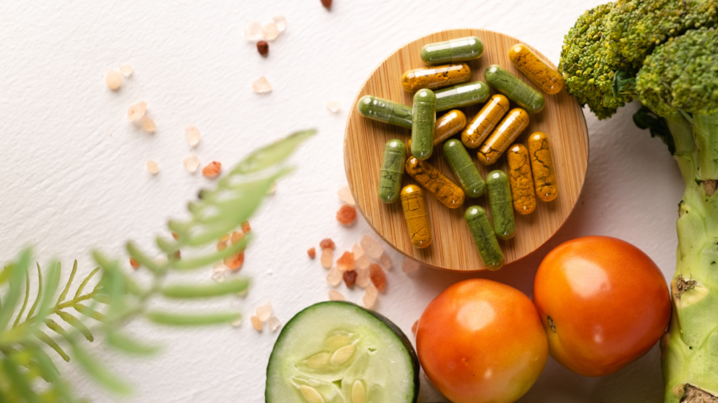 Natural Demodex skin support supplements with fresh vegetables, featuring green and turmeric-colored capsules beside broccoli, cucumber, and tomatoes.